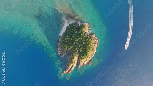 Aerial footage of a boat going around Arkhurst Island, a small islet near Hayman Island, a luxury resort hotel in the Whitsunday Islands group near the Great Barrier Reef in Queensland, Australia. photo