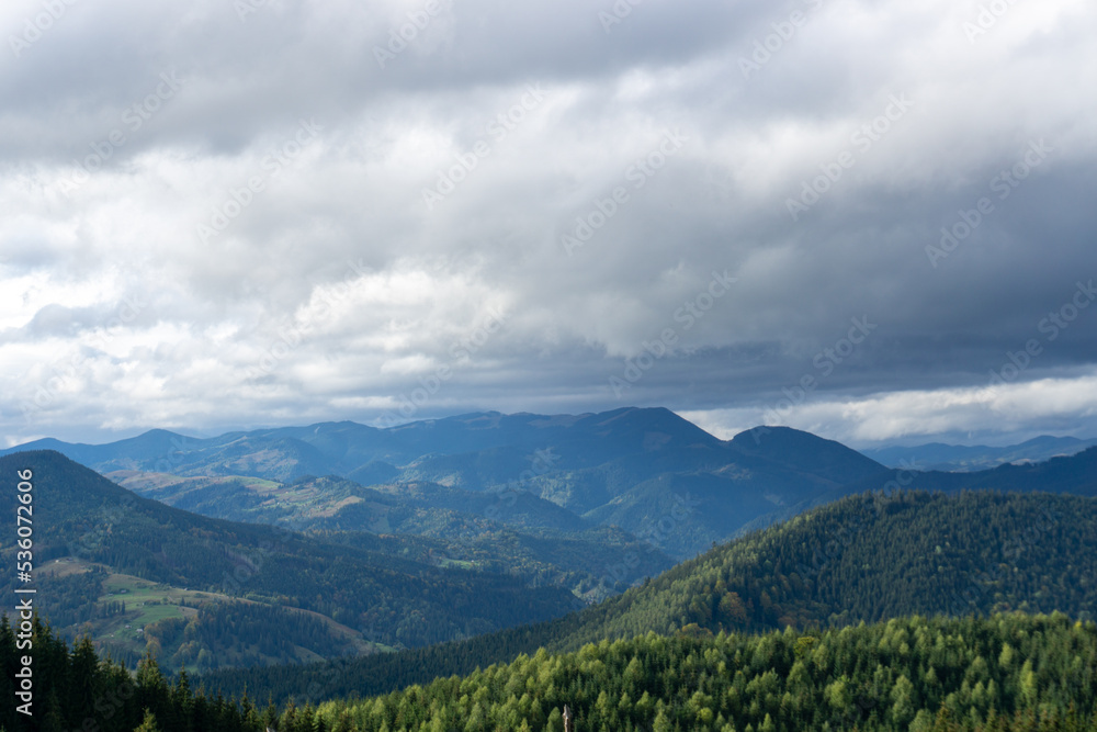 Panorama of forest covered by low clouds. Autumn rain and fog on the mountain hills. Misty fall woodland.