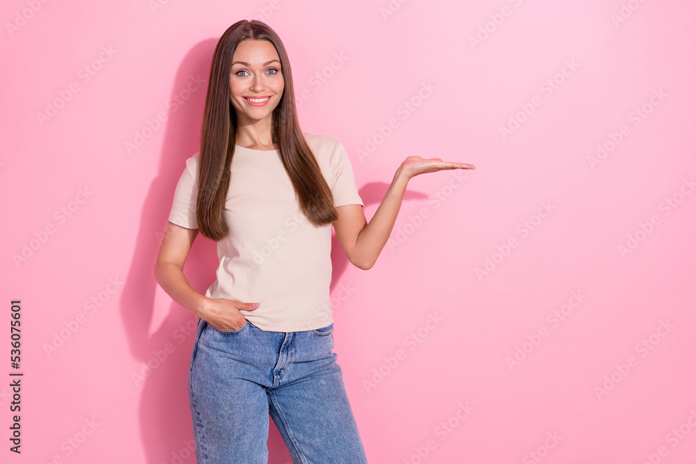 Photo of pretty positive person beaming smile arm palm hold empty space isolated on pink color background Photo of pretty positive person beaming smile arm palm hold empty space isolated on pink color background