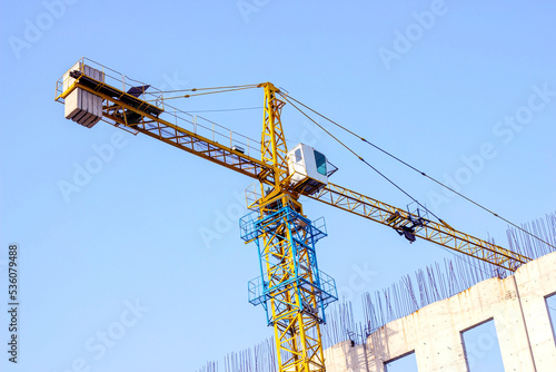 High crane for house building at the construction site on blue sky background.