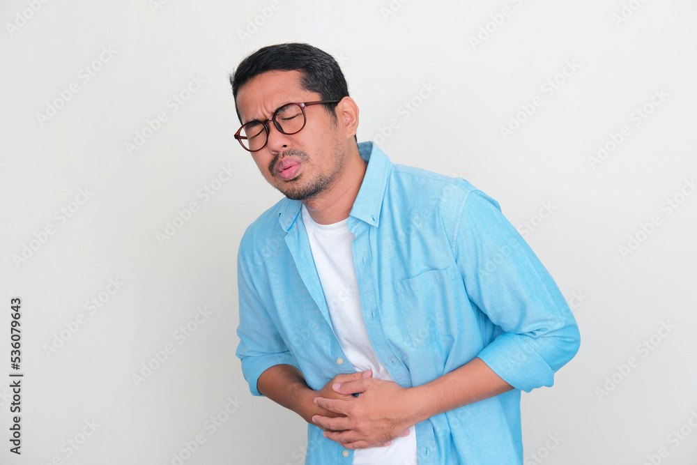 Adult Asian man suffering painful stomach ache Adult Asian man suffering painful stomach ache