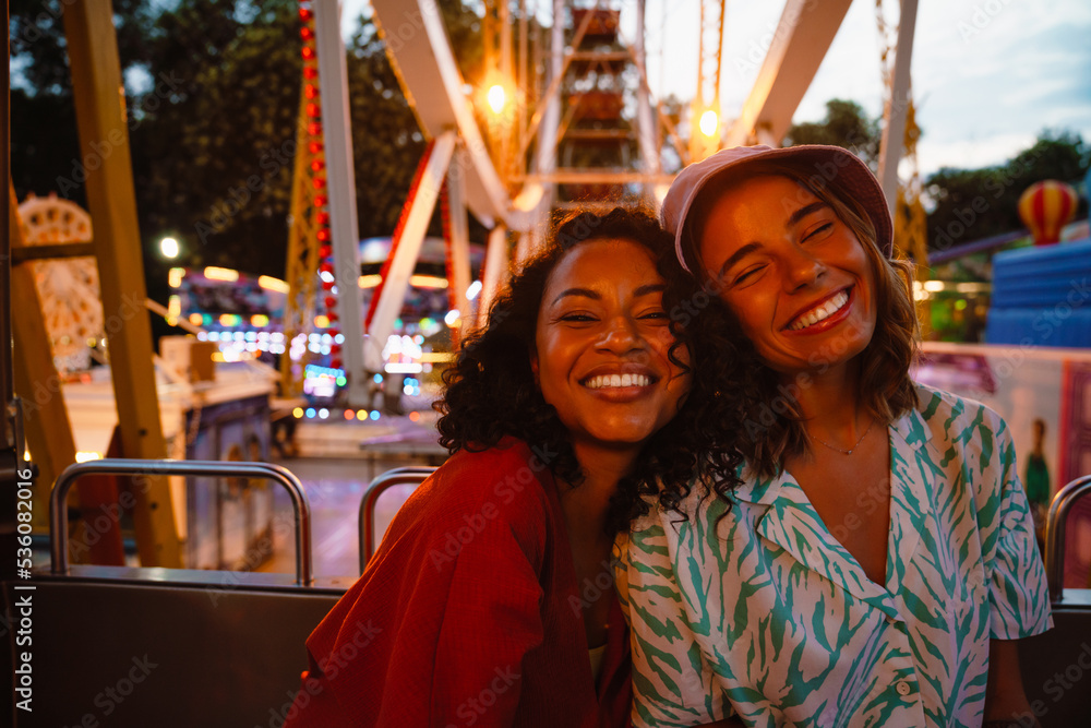 Fototapeta premium Young multiracial women riding on ferris wheel in attraction park