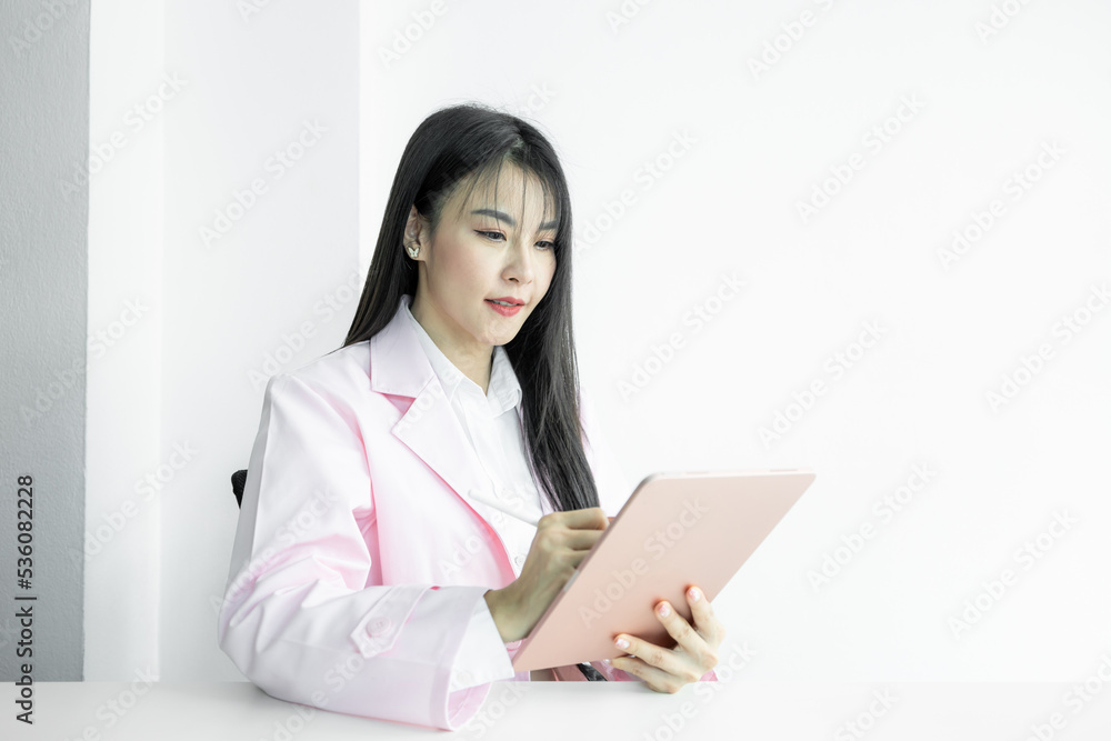 Asian woman doctor using digital tablet gadget technology on white background, Asian woman doctor in pink coat with digital tablet, Medical and healthcare working diagnosing examination health. Asian woman doctor using digital tablet gadget technology on white background, Asian woman doctor in pink coat with digital tablet, Medical and healthcare working diagnosing examination health.