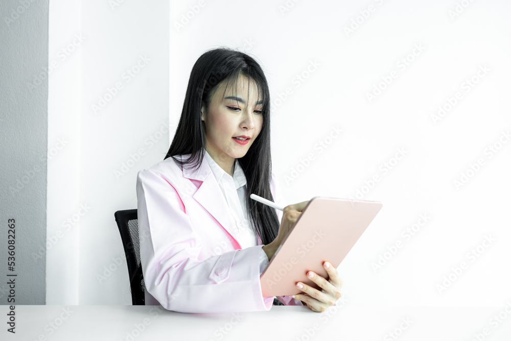 Asian woman doctor using digital tablet gadget technology on white background, Asian woman doctor in pink coat with digital tablet, Medical and healthcare working diagnosing examination health. Asian woman doctor using digital tablet gadget technology on white background, Asian woman doctor in pink coat with digital tablet, Medical and healthcare working diagnosing examination health.