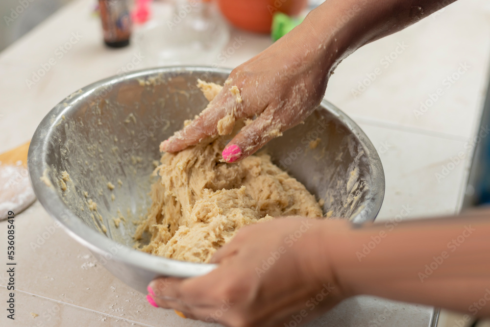 Fototapeta premium woman's hands kneading ingredients to make pan de muerto
