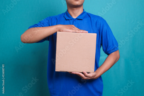 Close up picture of delivery man in blue uniform work as dealer courier hold a blank cardboard box