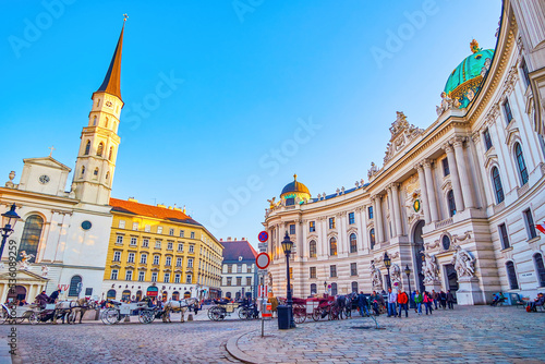 Evening on Michaelerplatz with lines of tourist horse-drawn carriages at Hofburg Palace in Vienna, Austria photo