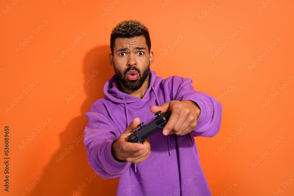 Photo of funny excited dude boy man have fun chill use playstation isolated on vivid orange color background Photo of funny excited dude boy man have fun chill use playstation isolated on vivid orange color background