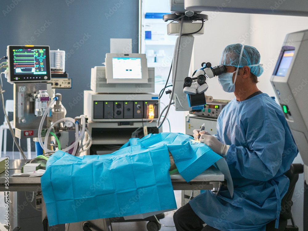 Surgeon using microscope in operating theater Surgeon using microscope in operating theater