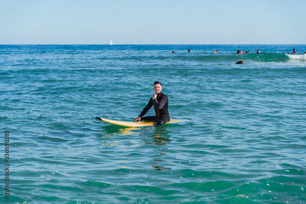 Man sitting on surfboard in sea water Man sitting on surfboard in sea water