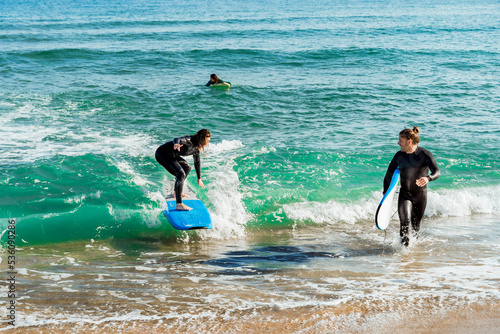 Young friends surfing in wavy sea photo