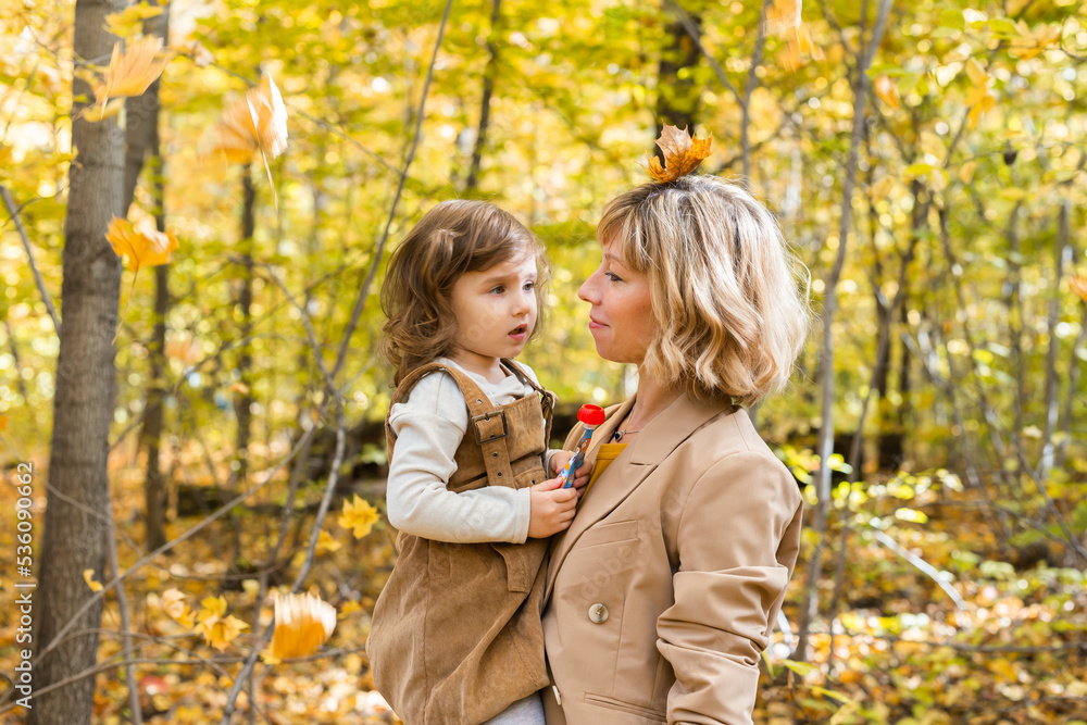 Mother with child in her arms against background of autumn nature. Family and season concept. Mother with child in her arms against background of autumn nature. Family and season concept.