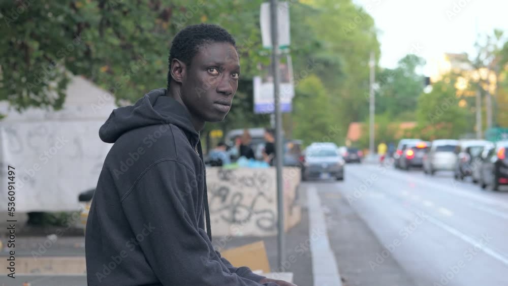 Black man looking away contemplating sitting on a low wall Black man looking away contemplating sitting on a low wall