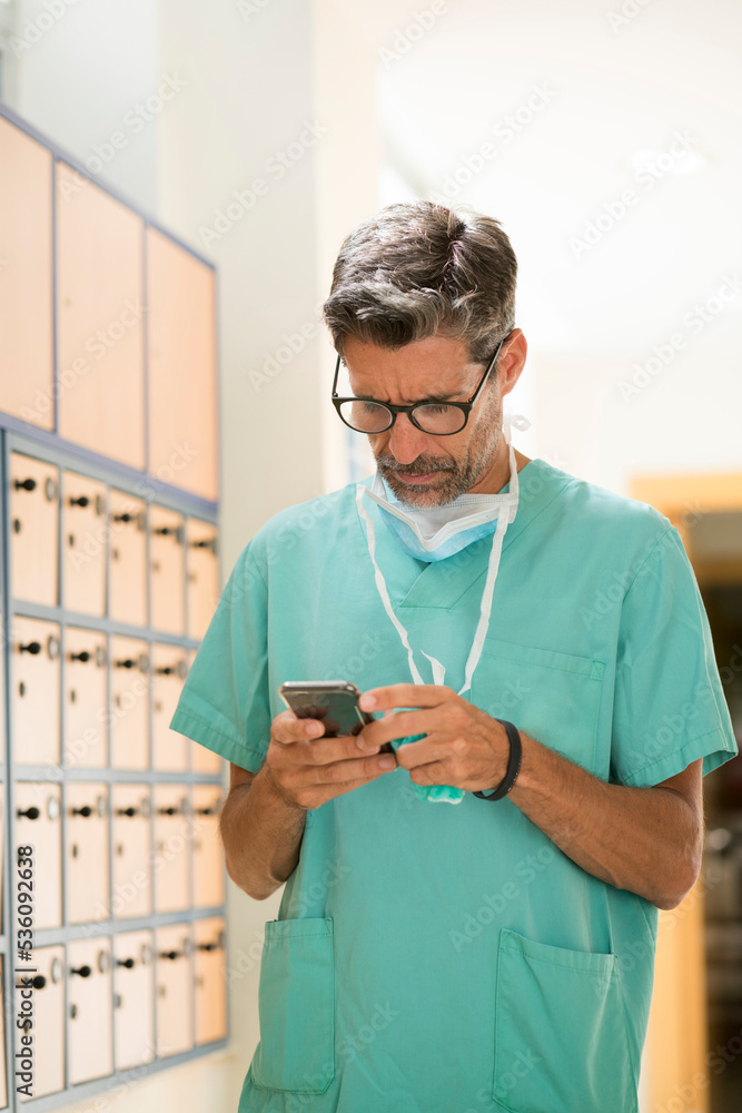 Serious surgeon using smartphone Serious surgeon using smartphone