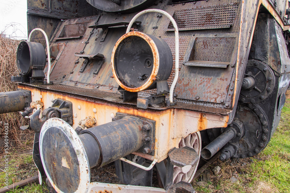 Drive transmission mechanism in a historic and damaged steam locomotive standing on a sidetrack. Rail.