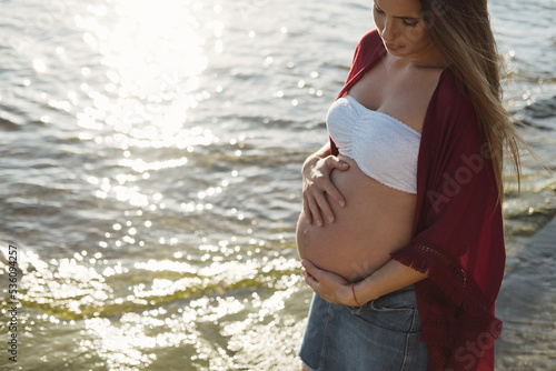 Pregnant female standing on stone near sea photo
