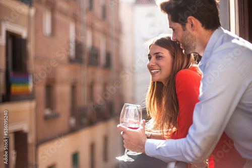 Happy couple with wine standing on balcony photo