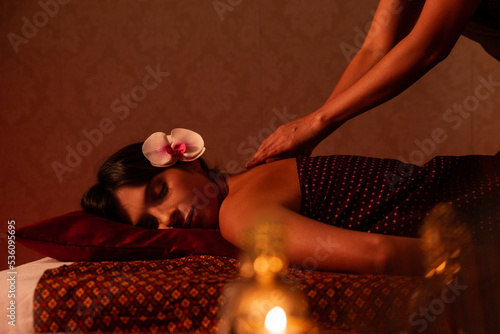 Anonymous thai female massagist giving a massage to a young woman photo
