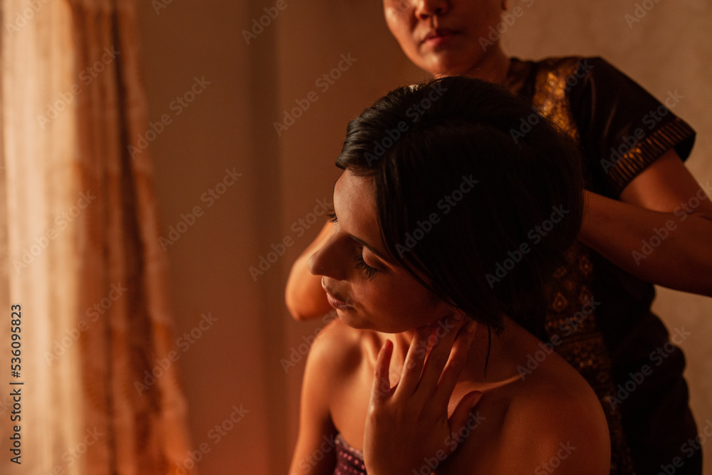 Thai female massagist giving a massage to a young woman Thai female massagist giving a massage to a young woman