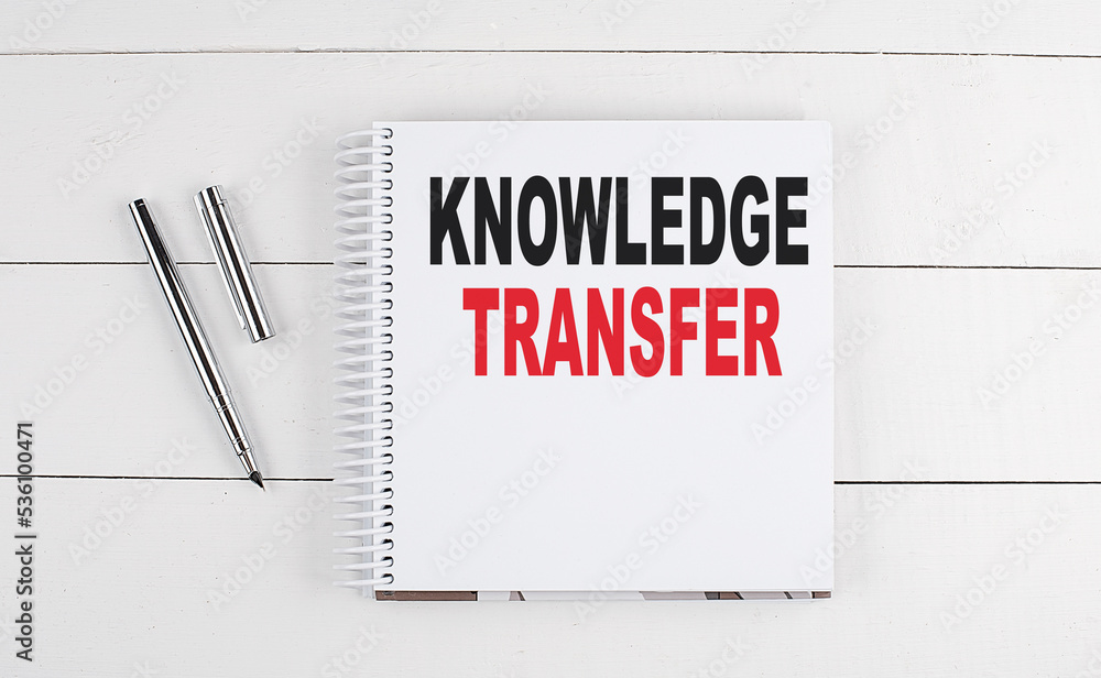 KNOWLEDGE TRANSFER text written on notebook on the wooden background KNOWLEDGE TRANSFER text written on notebook on the wooden background