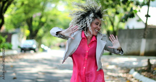 Ecstatic woman jumping with joy celebrating success outside in street