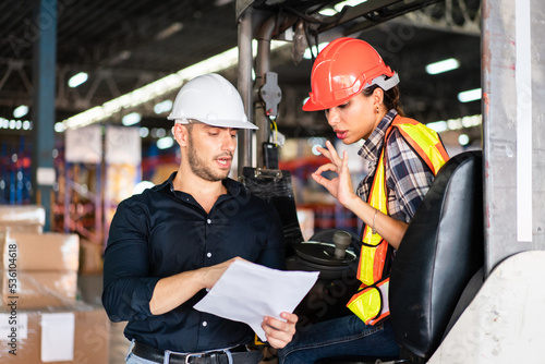 Male factory foreman holding document discuss and explain work project to female worker on forklift in the industry warehouse. Logistic shipping delivery career.