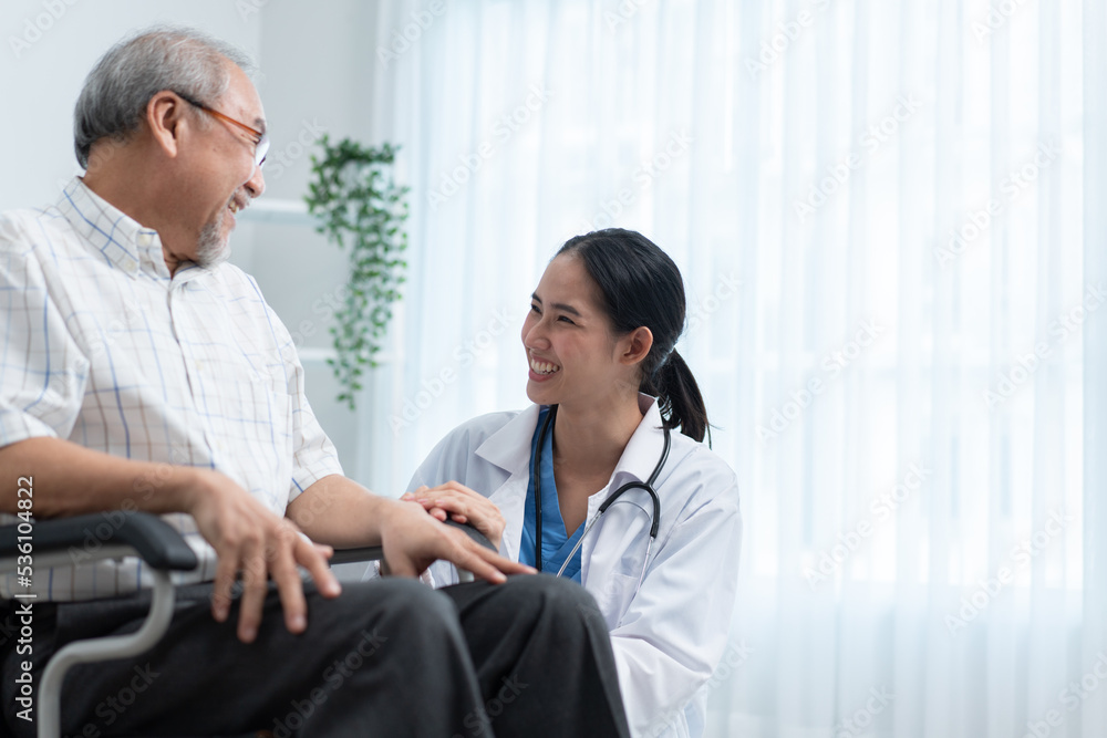 Fototapeta premium Asian female doctor telling funny story to senior man sitting on wheelchair. Grandfather laughing and happy at nursing home. Tae care and support aged people.
