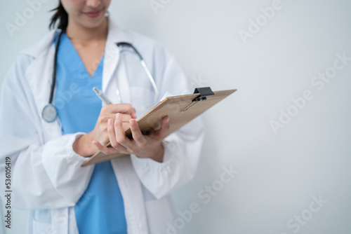 Asian female doctor with stethoscope writing on patient clipboard. Medical Healthcare career