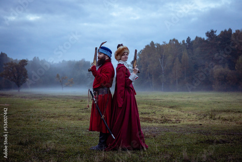 Fotografi Duel of a man and a woman in 17th century costumes using antique pistols