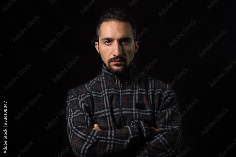Portrait of a serious man with folded hands on a black background. Stylish male portrait Portrait of a serious man with folded hands on a black background. Stylish male portrait