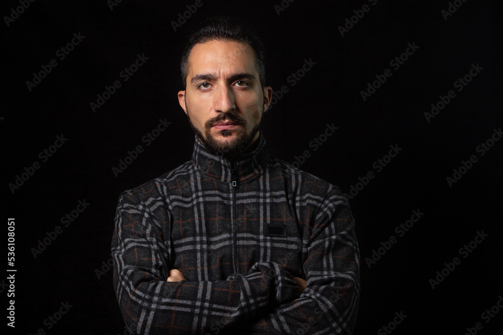 Portrait of a serious man with folded hands on a black background. Stylish male portrait Portrait of a serious man with folded hands on a black background. Stylish male portrait