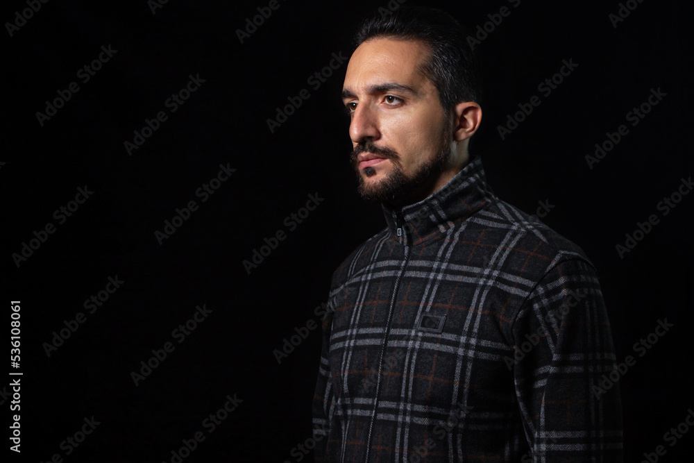 Portrait of a guy in a tracksuit on a black background. Stylish male portrait