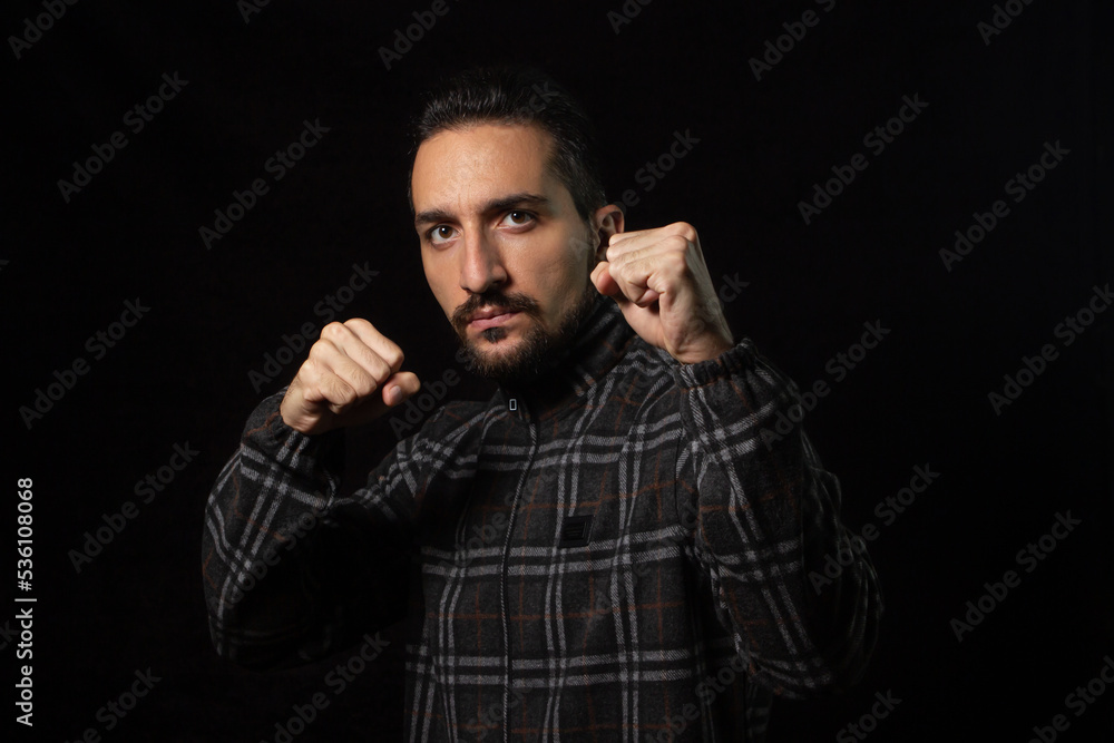 Portrait of a man in a combat stance on a black background. Stylish male portrait Portrait of a man in a combat stance on a black background. Stylish male portrait