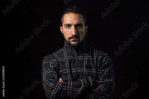 Portrait of a serious man with folded hands on a black background. Stylish male portrait