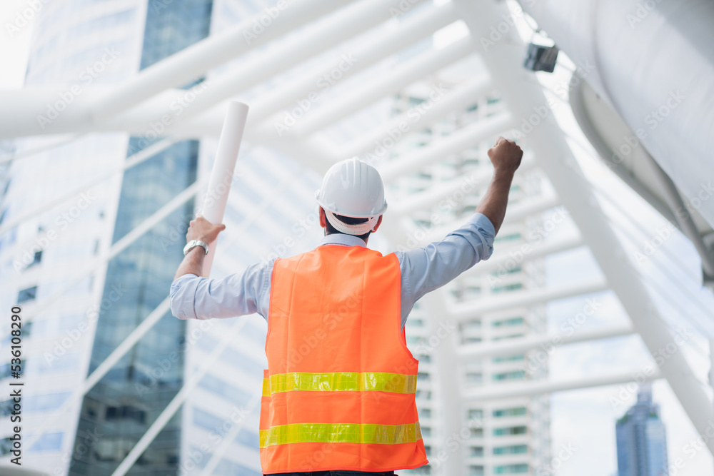 Man engineer standing on construction site. Engineer working on outdoor project and raising hands Man engineer standing on construction site. Engineer working on outdoor project and raising hands