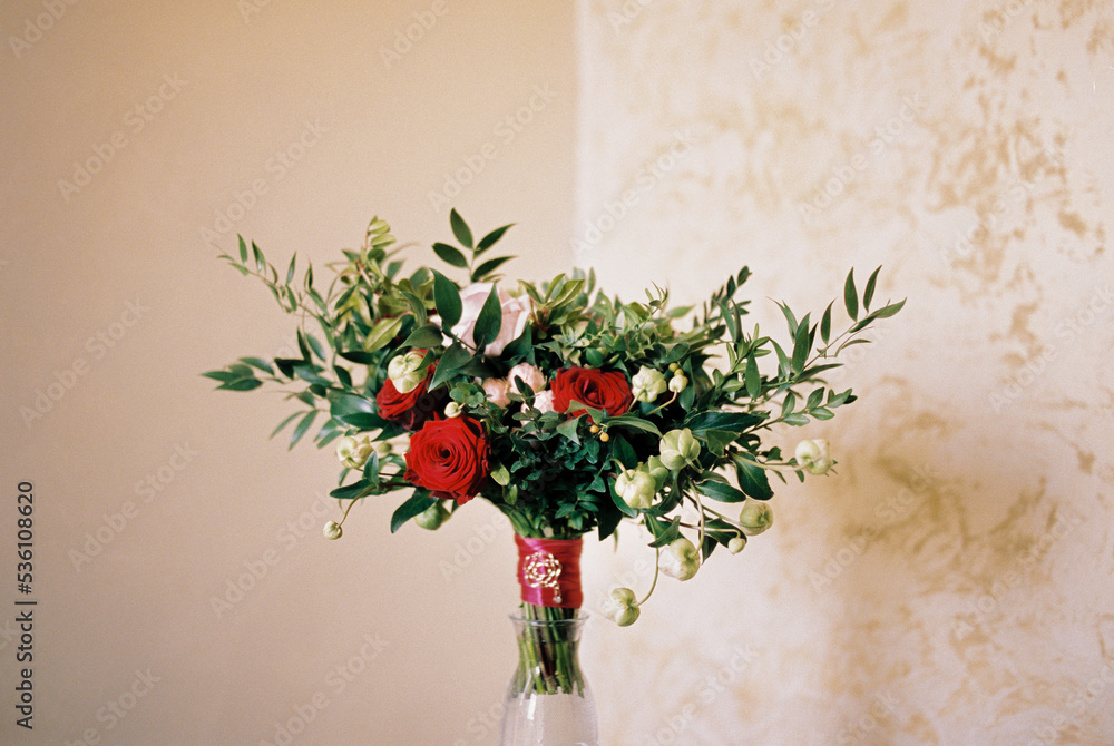 Bouquet of flowers stands in a vase against the wall