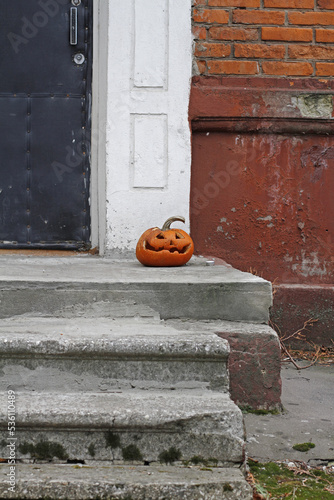 Scary pumpkin as halloween decoration stands at the front door on the street