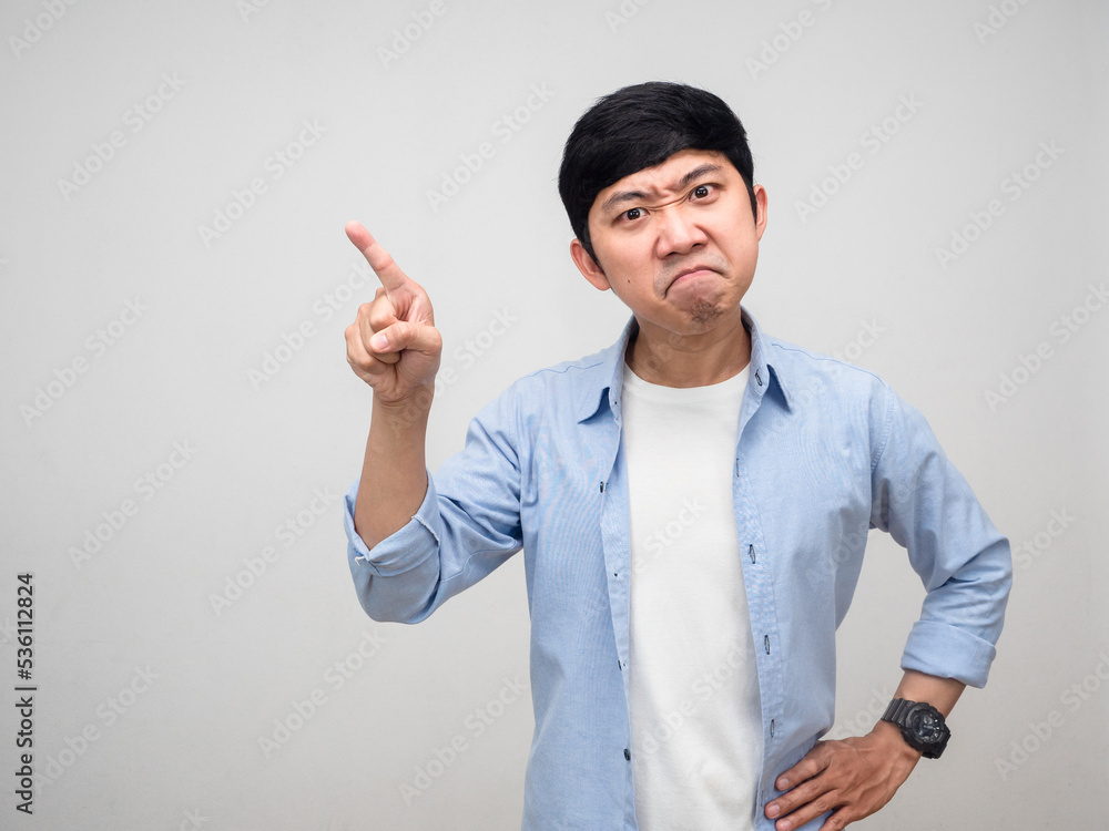 Angry young man blue shirt hand at waist and point finger isolated Angry young man blue shirt hand at waist and point finger isolated