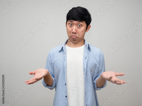Confused asian man blue shirt posing hands up I don't know isolated