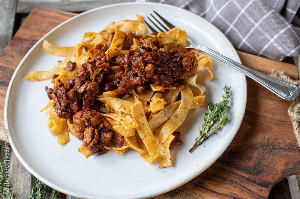 Italian ragout with chicken, tomatoes, onions, garlic, herbs and red wine sauce on a plate with tagliatelle Italian ragout with chicken, tomatoes, onions, garlic, herbs and red wine sauce on a plate with tagliatelle