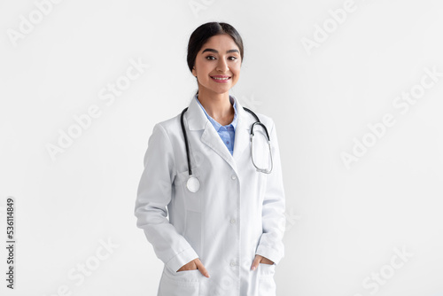 Fotografija Portrait of confident smiling millennial indian female doctor in white coat with
