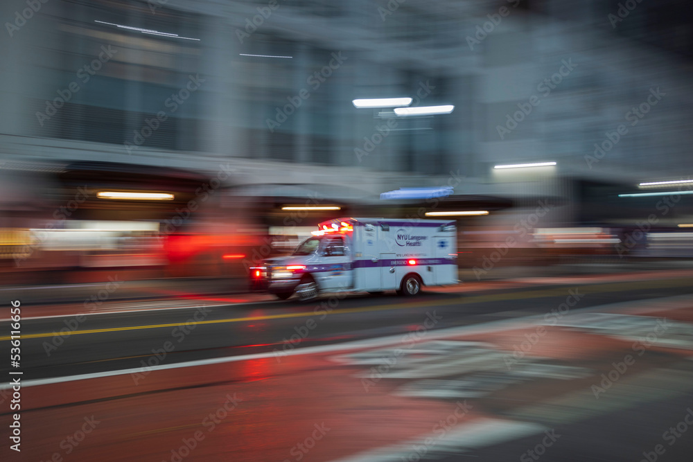 Beautiful out of focus night cityscape road view. Racing Ambulance car on front. New York. 