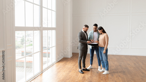 Couple Buying New Apartment, House Agent Showing Documents Blueprints © Prostock-studio