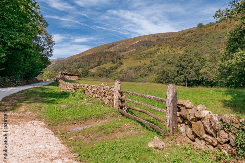 sendero y muro de piedra con valla de madera en un paisaje de montaña