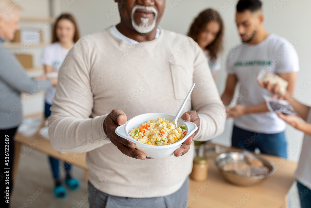 African american senior man holding plate with meal, receiving food in charity organization office, cropped, closeup African american senior man holding plate with meal, receiving food in charity organization office, cropped, closeup