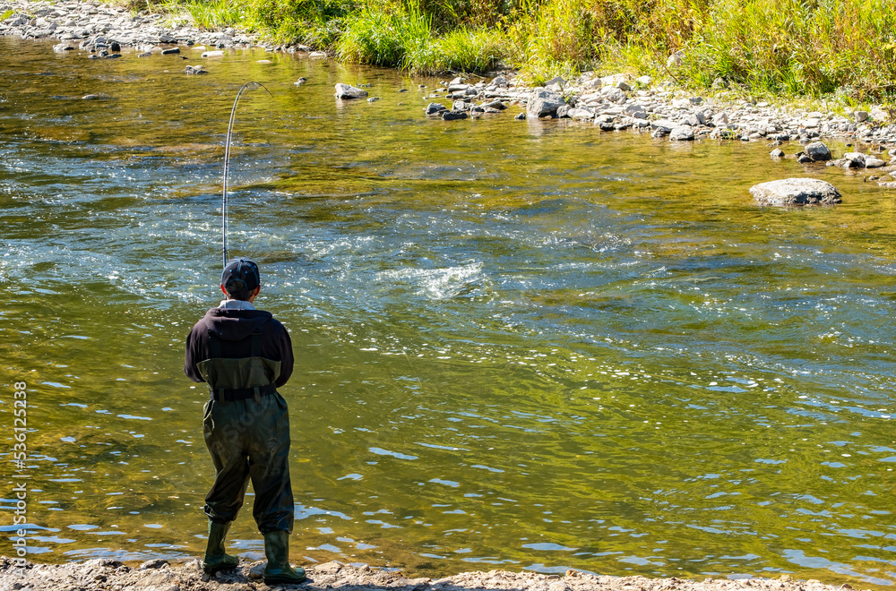 A Fisherman Standing by Credit River Shore Trying to Catch a Fish During the Annual Fall Salmon Run A Fisherman Standing by Credit River Shore Trying to Catch a Fish During the Annual Fall Salmon Run
