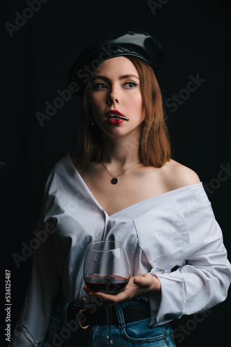 A young beautiful woman with dark hair and a beret on her head, with a glass of wine and a cigarette, A close-up portrait. Parisian style. © Anastasia