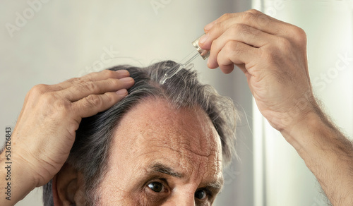 Old man dropping serum onto his hair