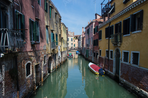 Un canale di Venezia con una piccola barca ormeggiata e coperta da un telo rosso photo