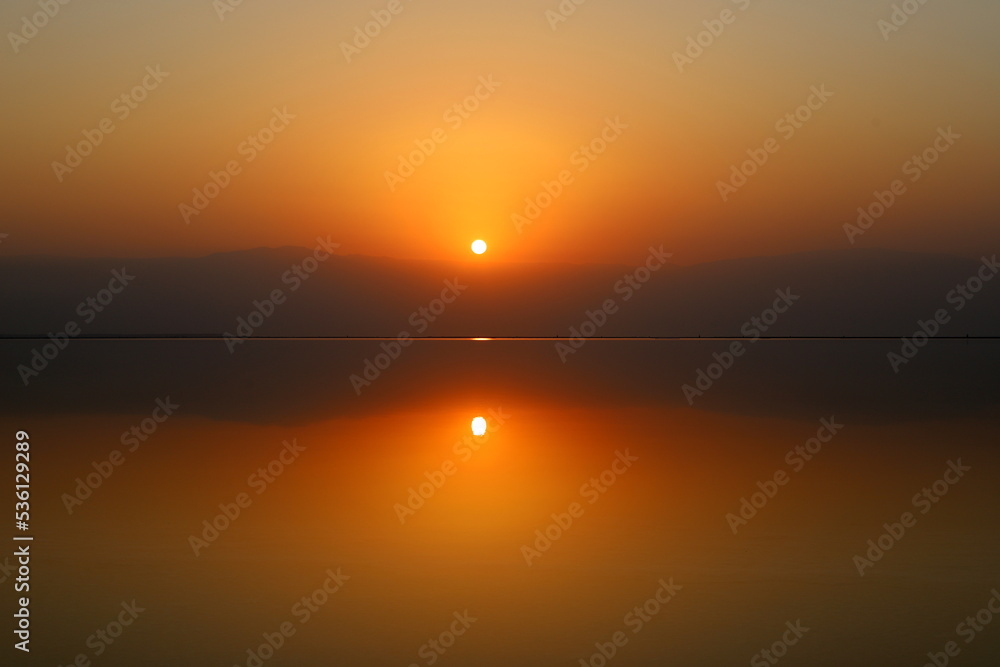 Fototapeta premium Sunrise on the shore of the Dead Sea in Israel. The sun rises from behind the mountains in Jordan.
